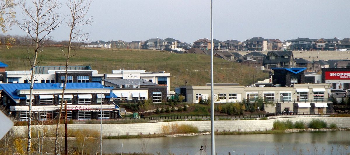 Aspen Landing shopping village beside a pond in Aspen Woods, Calgary, with houses on the hill behind, in 2010.