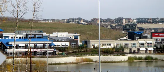 Aspen Landing shopping village beside a pond in Aspen Woods, Calgary, with houses on the hill behind, in 2010.